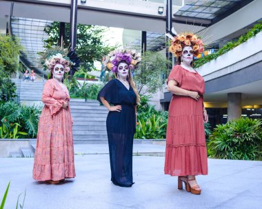 Kadınlar katrinas olarak uydurulmuş. Ölüler günü ve Cadılar Bayramı makyajı. Üç kadının açık hava grup portresi