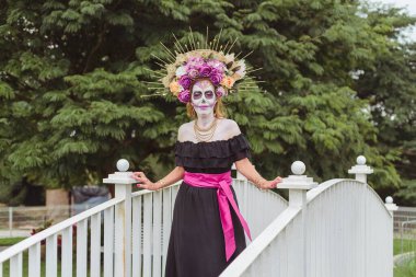 Catrina kılığına girmiş bir kadın. Meksikalı kadın ölüm gününü kutluyor. Cadılar Bayramı makyajlı açık hava portresi.