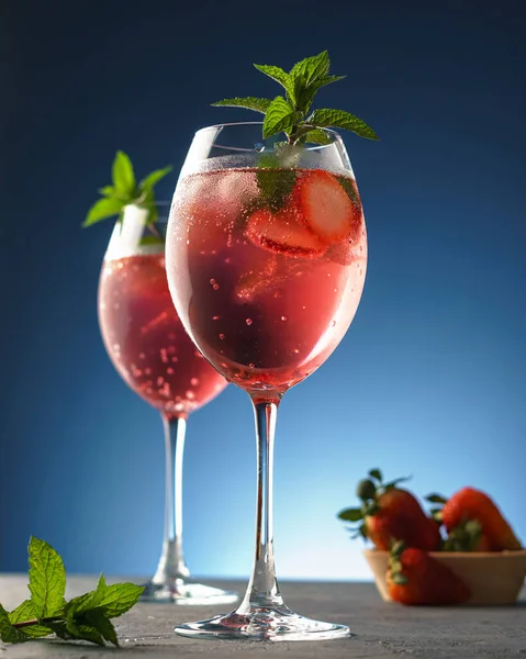 Strawberry gin and tonic decorated with peppermint. Blue background.