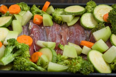 Çiğ balık fileto ve sebzeli tepsi ahşap masada. Sağlıklı yemek..