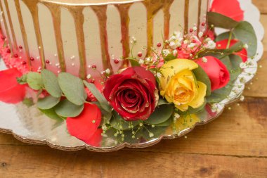 Kek ahşap bir masada güllerle süslenmiş..