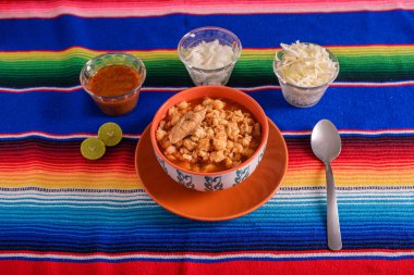 Kırmızı pozole renkli bir tabakta servis ediliyor. Tipik Meksika yemekleri mısırdan yapılır.