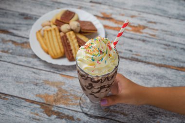 Tahta masada kremalı çikolatalı milkshake. Bir kadının eli milkshake 'i tutuyor.