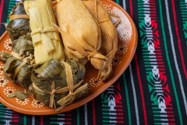 Meksika bayrağının renginde, masa örtüsünün üzerindeki kil tabaktaki farklı tamaleler..