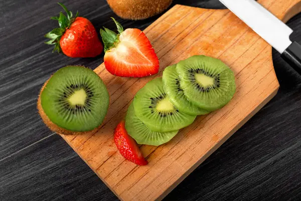 Cut fruits on a wooden board. Cut kiwi and strawberries.