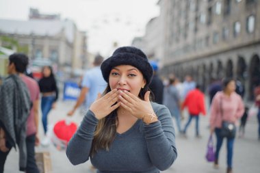 Sokağın ortasında şaşırmış tavırlı Latin bir kadın. Arka plandaki insanlar.