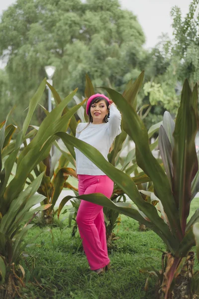 Mexican woman among plants wearing pink beret. Mexican woman with positive attitude.