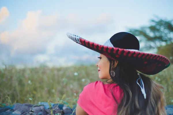Mexican woman wearing typical Mexican hat. Outdoor portrait next to stone wall.