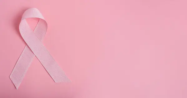 Pink ribbon on pink paper background. Breast cancer ribbon.