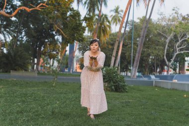 Kamu parkında pozitif tavırlı bir kadın kameraya bakıyor ve öpücük yolluyor..