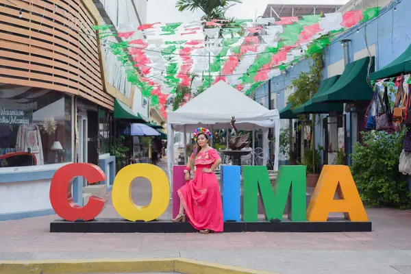 Colima şehrinin dev harflerinin yanında geleneksel bir kostüm giyen Meksikalı kadın. Cinco de Mayo kutlaması.