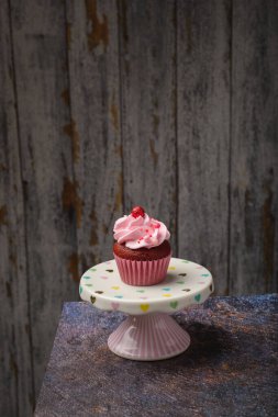 Küçük seramik tabakta kekin altında tahta tabaka ve fotokopi alanı var. Ürün fotoğrafı..