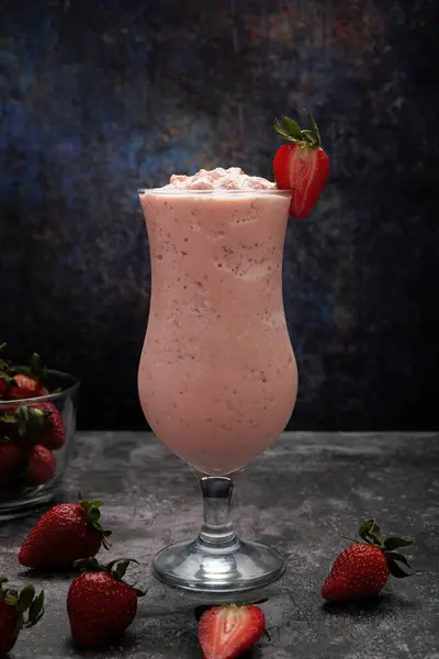 Strawberry milkshake on cement table with dark background. Strawberry frappe.