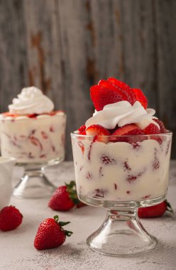 Çilek ve krema, cam bardakta çimento masasının üstünde. Boşluğu kopyala.