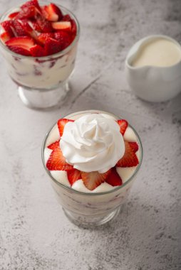 Çilek ve krema, cam bardakta çimento masasının üstünde. Boşluğu kopyala.