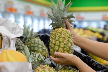 Kadın eli süpermarketin rafından ananas topluyor..