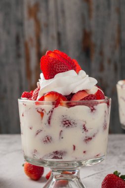 Çilek ve krema, cam bardakta çimento masasının üstünde. Boşluğu kopyala.