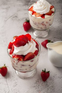 Çilek ve krema, cam bardakta çimento masasının üstünde. Boşluğu kopyala.
