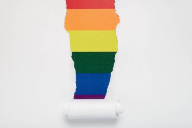 Torn hole in white paper revealing the LGTBQ flag . Rainbow flag.