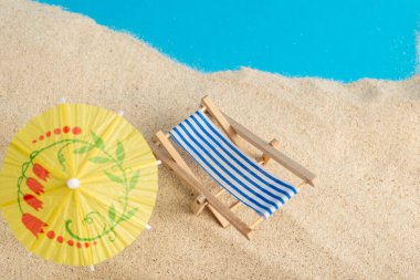Deniz kumu, kokteyl şemsiyesi, deniz yıldızı ve plaj sandalyesi olan yaz arkaplanı. Metin için boşluk.