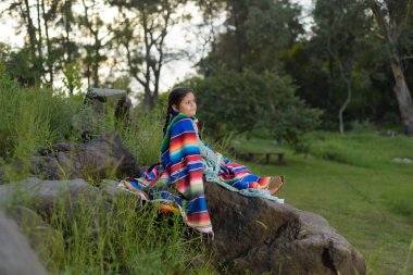 Kırsal bir yerde serapın içine sıkışmış büyük bir elbise giyen küçük Meksikalı kız..