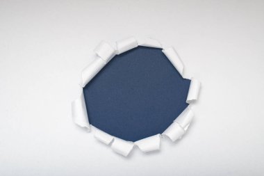 Beyaz kağıt, mavimsi-gri bir arkaplanı gösteren bir daire şeklinde yırtılmış. Metin için boşluk.