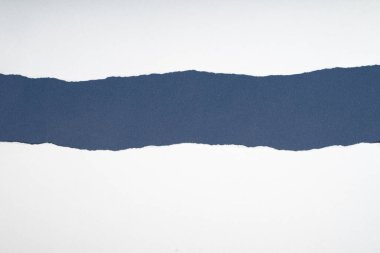 Yırtık beyaz kağıt, mavi-gri bir arkaplanı gösteriyor. Metin için boşluk.