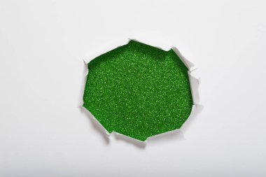 Beyaz kağıttaki ortadaki yırtık, arka planda yeşil parıltı dokusu olduğunu gösteriyor. Metin için boşluk.