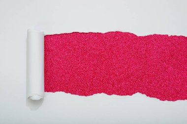 Yırtılmış beyaz kağıt, koyu pembe parıltılı arka plan gösteriyor. Metin için boşluk.