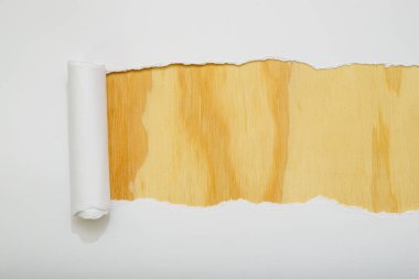 Tahta arka planı ortaya çıkaran yırtık beyaz bir kağıt. Metin için boşluk.