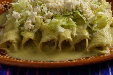 Kil tabakta servis edilen marul ve peynirli yeşil enchilada. Kapat..