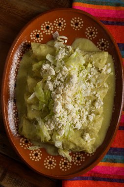 Kil tabakta servis edilen marul ve peynirli yeşil enchilada. Kapat..