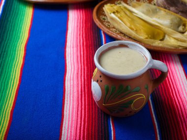Renkli serapla kaplanmış kil bardak. Tamale 'ler arka planda. Meksika yemeği.