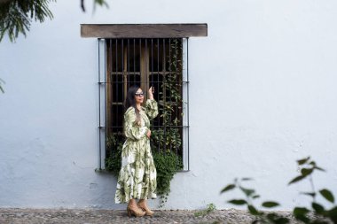 İşlenmiş demir parmaklıklı Vintage Pencere Tarafından Tropikal Baskı Giyinen Şık Kadın.