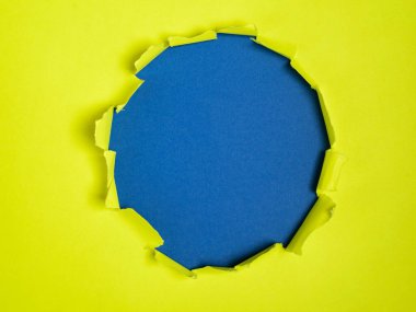 Sarı kağıtta ortadaki yırtık delik mavi arkaplan, metin için boşluk gösteriyor.