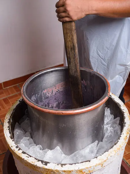 Bir insan metal bir kapta dondurma karışımı yapmak için tahta kürek kullanır. Geleneksel dondurma yapma süreci.