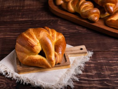 Yeni pişmiş bir kruvasan, çarşaf bezine yerleştirilmiş, ahşap bir tahtanın üzerinde duruyor..
