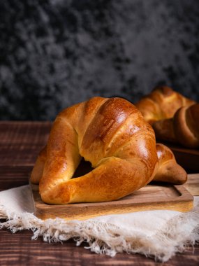Yeni pişmiş bir kruvasan, çarşaf bezine yerleştirilmiş, ahşap bir tahtanın üzerinde duruyor..