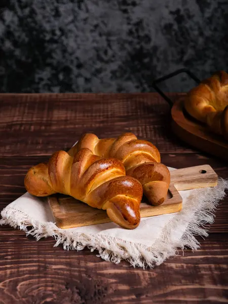 İki yeni pişmiş kruvasan, altın rengi kahverengi ve pırıl pırıl, ahşap bir tahtanın üzerinde keten bir kumaşın üzerinde dinleniyor..