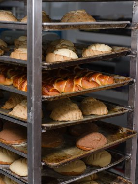 Fırından yeni çıkmış ekmeklerle dolu metal bir raf..