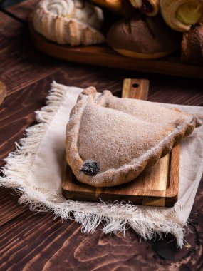 İki lezzetli böreğin yakın çekimi şekerle kaplanmış, kırsal bir tahtanın üzerinde dinleniyor..