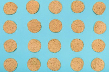 Açık mavi-yeşil arkaplanda dikkatlice dizilmiş sayısız yuvarlak nachos..