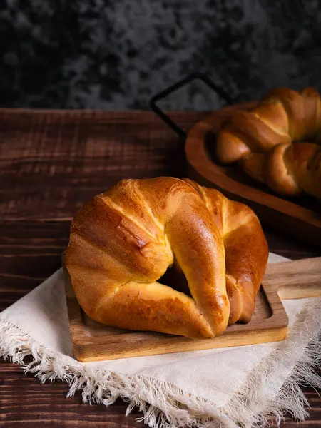Yeni pişmiş bir kruvasan, çarşaf bezine yerleştirilmiş, ahşap bir tahtanın üzerinde duruyor..