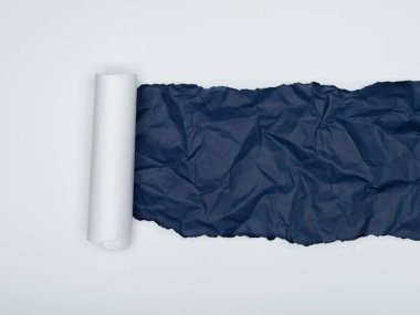 Bir parça beyaz kağıt, altında koyu mavi, buruşmuş bir kağıt tabakasını ortaya çıkarmak için yırtılır..
