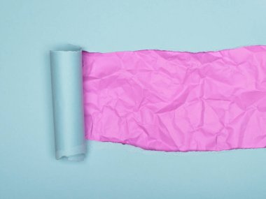 Açık mavi yırtık kağıt altında pastel pembe bir arka plan ortaya çıkarıyor..