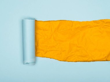 Yırtık bir açık mavi kağıt parçasını gösteren canlı bir görüntü altında buruşuk, parlak sarı bir kağıt tabakasını ortaya çıkarıyor.