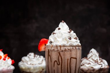 Koyu arkaplanda uzun bir bardakta servis edilen çikolatalı milkshake. Ayrı bir içki. Kapat..