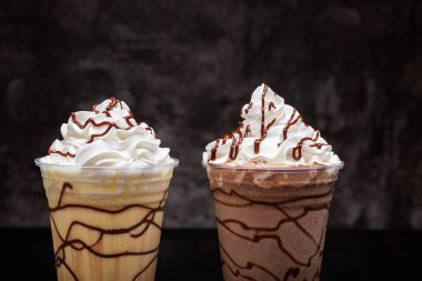 Vanilyalı ve çikolatalı milkshake, siyah arka planda berrak bardakta çikolata şurubu..