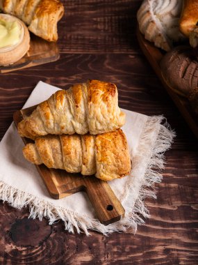 Taze pişmiş hamur işlerinin baştan çıkarıcı bir çeşidi, kaymaklı muhallebi dolu hamur tatlısı kırsal ahşap bir tahtada sergileniyor..