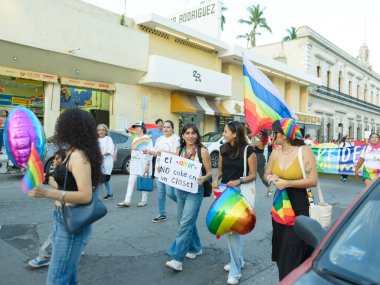 Colima, Colima. Meksika; 21 Haziran 2025: Gökkuşağı bayrakları ve LGBTQ + haklarını savunan tabelalar taşıyan Onur Yürüyüşü katılımcıları.